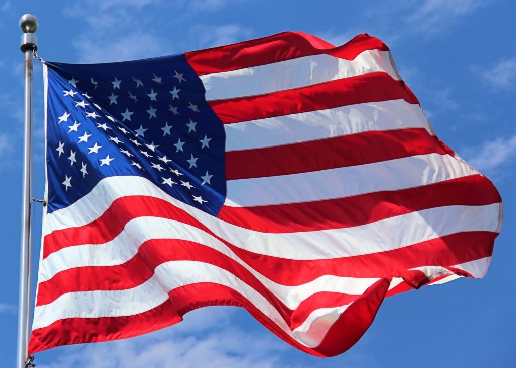 American flag waving, symbolizing the religious freedom and divine providence celebrated on America's 250th anniversary