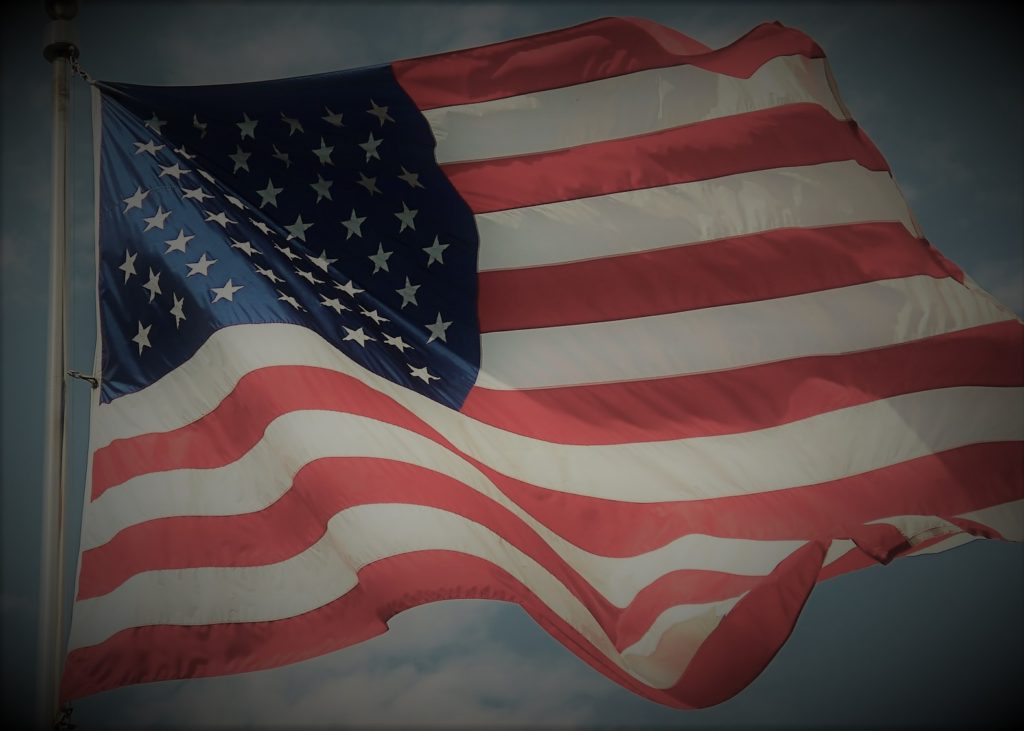 American flag waving, representing the Revolutionary War era when Peter Muhlenberg preached his farewell sermon on January 21, 1776 and joined the fight for liberty (Ecclesiastes 3:8)